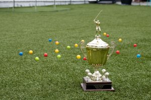 Photo of Kinetic Cup Trophy on roof astroturf with golf balls and scoring area behind
