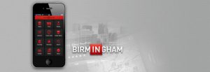 Photo of phone showing Birmingham App with faint images of city and gps map in background