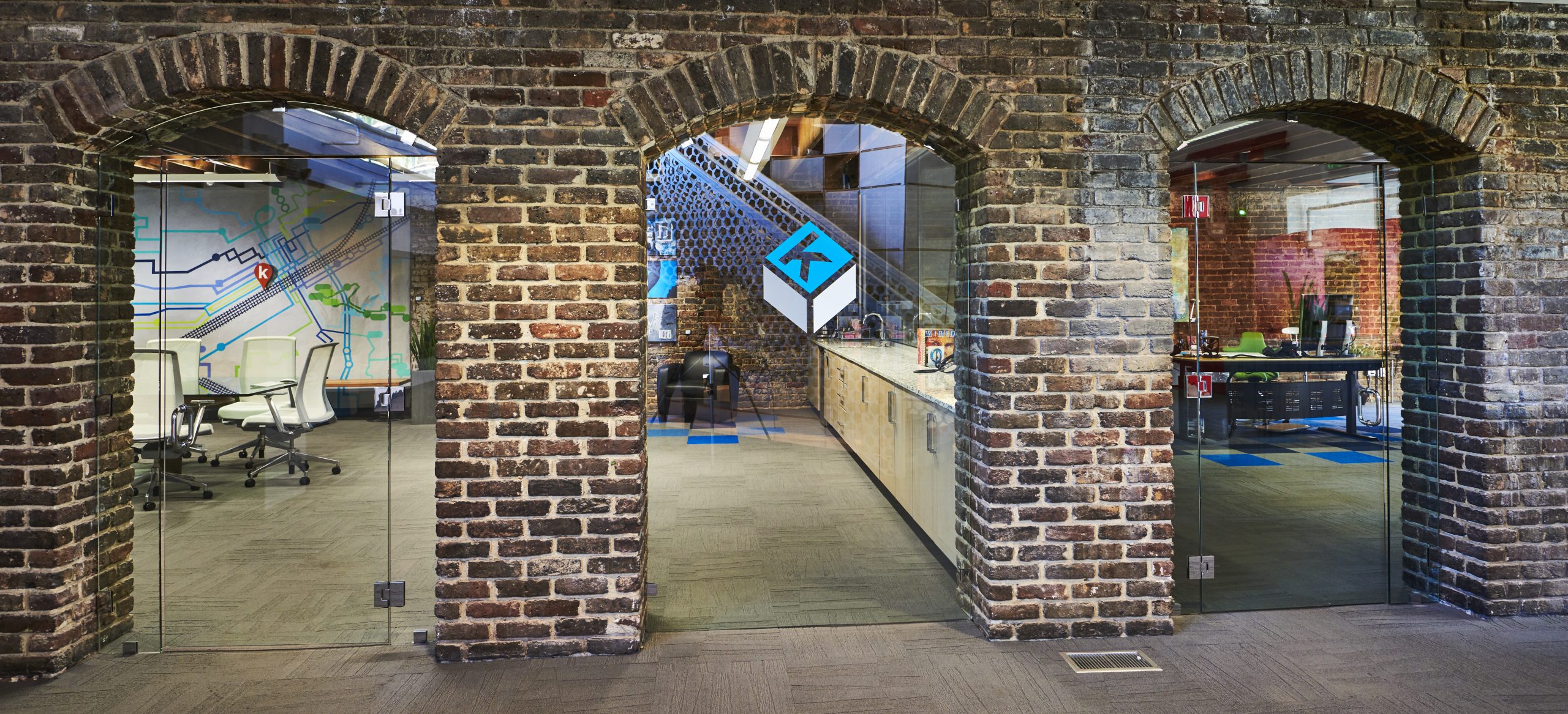 Photo of Kinetic's original brickwork archways on the east building. Each arch features a glass window or door.