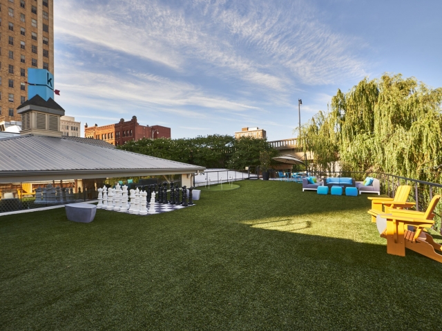Photo of the Kinetic's astroturf rooftop area complete with chairs, couches, chess set, and golf green.