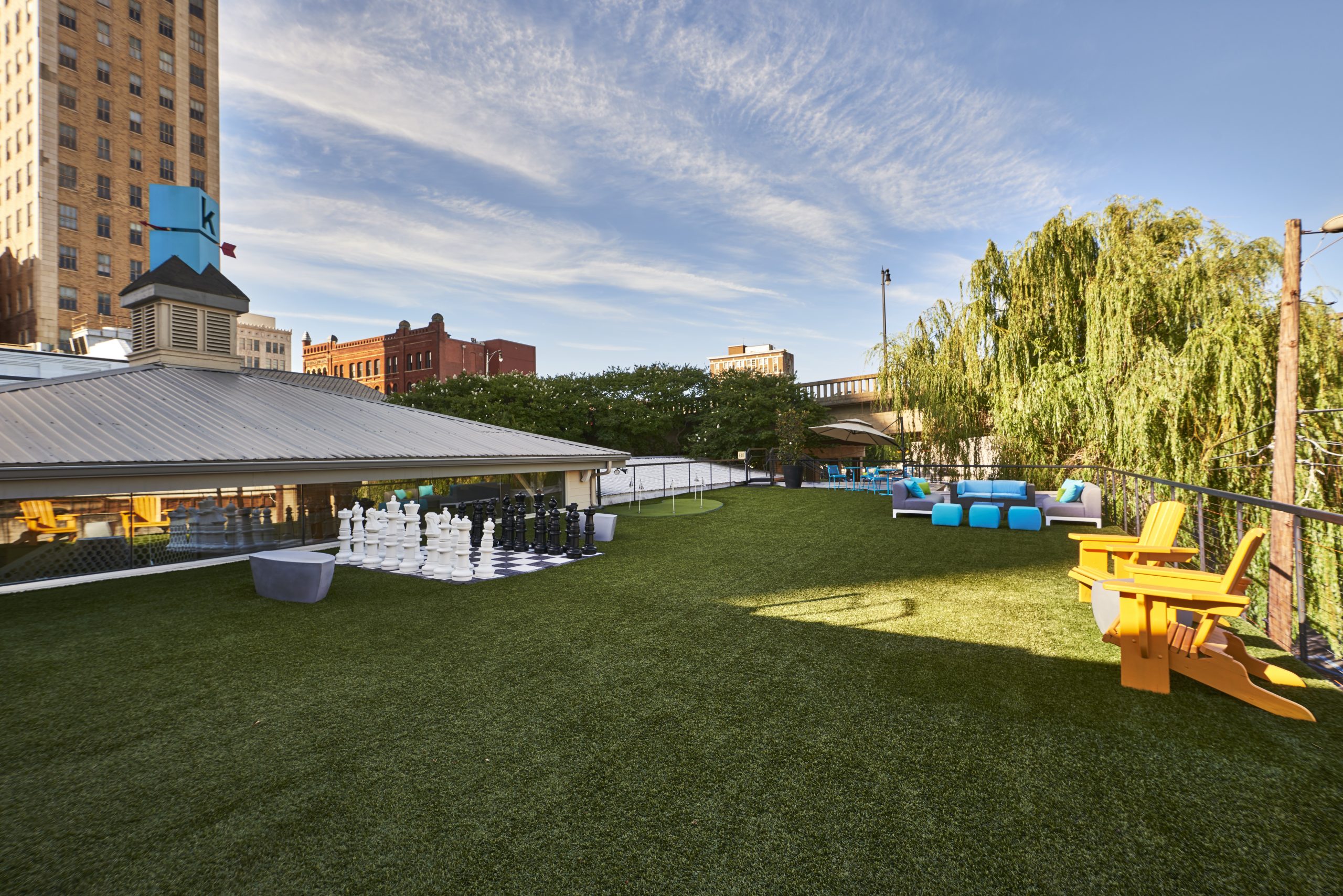 Photo of the Kinetic's astroturf rooftop area complete with chairs, couches, chees set, and golf green.